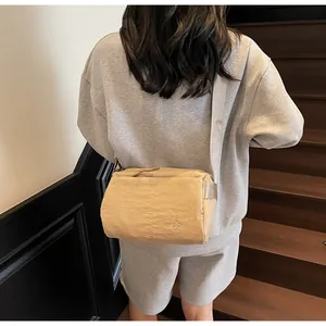 Khaki nylon crossbody bag with wide shoulder strap shown from a back side angle view