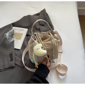 Detail of beige nylon drawstring bucket bag with top handle and plush moon charm