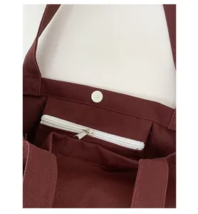 Detail of burgundy canvas tote bag featuring magnetic closure and inner zipper pocket