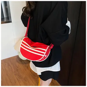 Detail view of red crescent canvas bag with three white stripes and adjustable strap