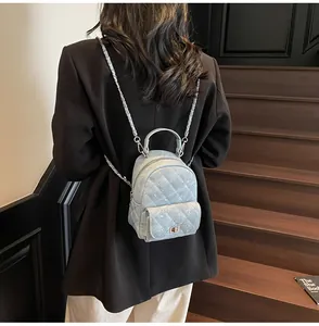 Close-up of mini quilted denim backpack with rhinestones and metal chain on model