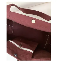 Detailed interior of burgundy canvas tote bag with zipper pocket and magnetic buckle