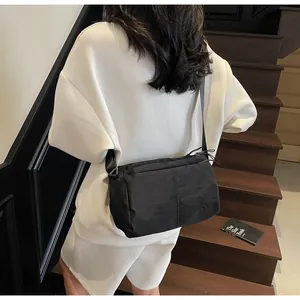 Detail of waterproof black nylon crossbody bag featuring embossed logo and zipper puller