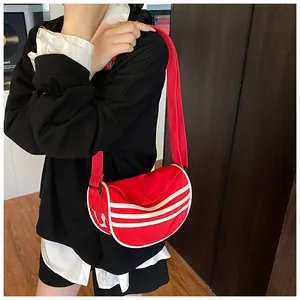 Detail of red canvas crescent bag with white stripes worn by a model in casual style