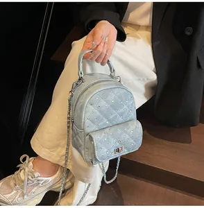 Close-up of quilted denim mini backpack with sparkling rhinestones and metal chain strap