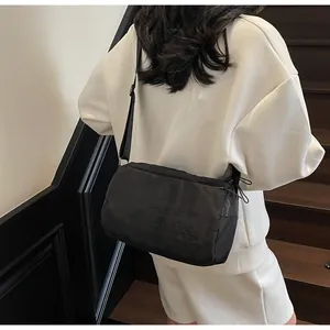 Detail of black waterproof nylon crossbody bag with adjustable strap and side drawstring
