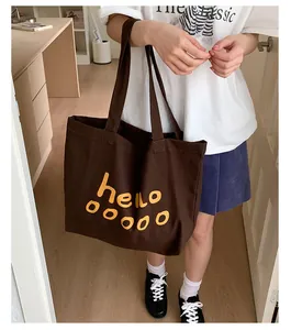 Detail of a deep brown canvas tote bag with yellow hello print in a cozy indoor setting