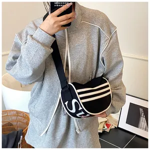 Detail of canvas crescent crossbody bag featuring bold SU logo and side stripes