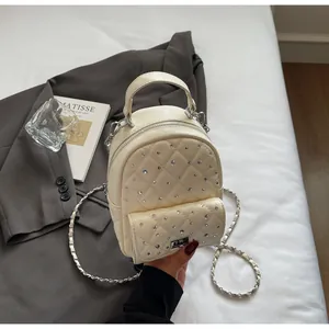 Detail of beige quilted mini backpack with rhinestone decor and silver chain straps