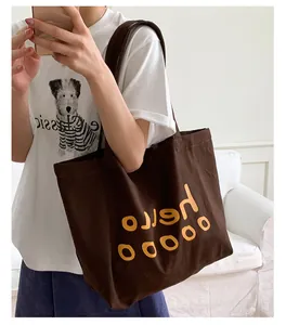 Detailed close-up of dark brown canvas tote bag with yellow hello ooooo letter print