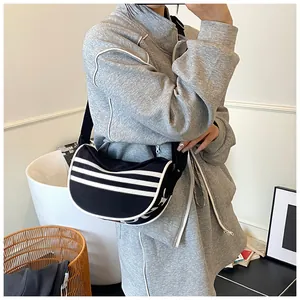 Close-up of black canvas crescent bag featuring sporty white stripes and wide strap
