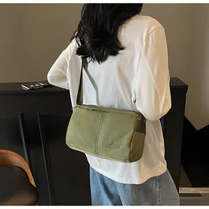 Rear view of model wearing an olive green crossbody bag with adjustable strap and logo