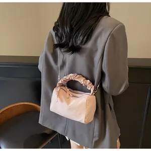 Sac polochon plissé rose avec chaîne en métal sur un mannequin en costume gris