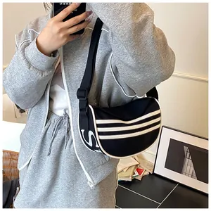 Detail of black crescent canvas bag showing sporty white stripes and wide shoulder strap