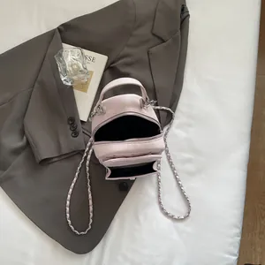 Pink quilted mini backpack with chain strap on a blazer, top-down lifestyle view