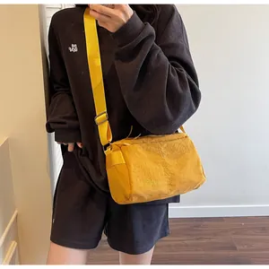 Model view of bright yellow nylon crossbody bag with wide adjustable strap and logo detail