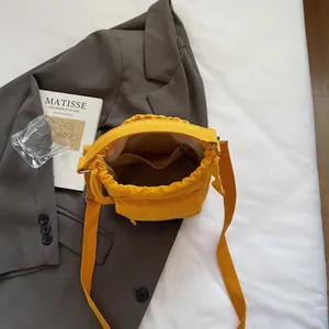 Yellow drawstring nylon bucket bag with inner zipper pocket shown on a stylish blazer