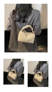 Détail de la poignée froncée beige et de la bandoulière chaîne d'un sac chic en similicuir