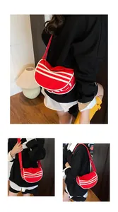 Detail view of red crescent canvas bag with white triple stripes and adjustable strap