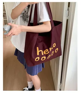Detail of burgundy canvas tote bag with yellow hello text and wide shoulder strap