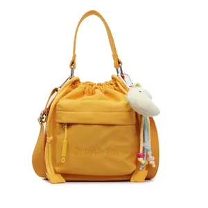 Bright yellow nylon drawstring bucket bag with adjustable strap and plush charm