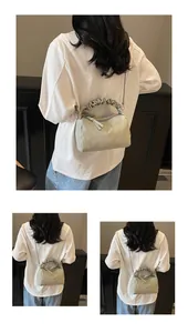 Détail du sac cylindrique plissé vert sauge avec chaîne argentée et poignée froncée