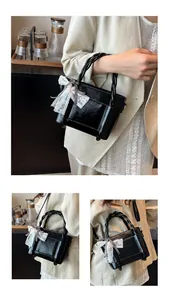 Détail du sac seau noir en cuir texturé avec poignée tressée et nœud en dentelle