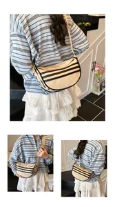Macro detail of beige canvas dumpling bag showing triple black stripes and wide strap