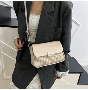 Detail of cream crossbody bag with woven texture on model in grey blazer