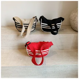 Detailed view of canvas crescent bags in khaki, black, and red with triple stripe design