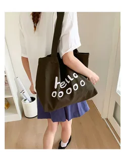 Detail of green canvas tote bag showing the white Hello letter print and durable material