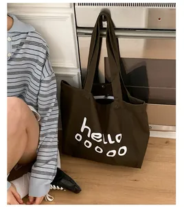 Detail of coffee brown canvas tote bag featuring large white hello print and soft texture