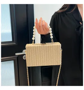 Detail of woven straw handbag featuring pearl handle and golden chain shoulder strap