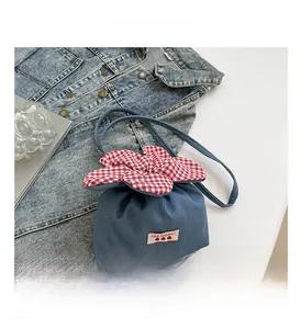 Detailaufnahme der Blumen-Beuteltasche aus blauem Denim mit Karomuster-Besatz