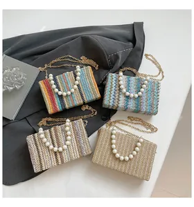 Detailed view of colorful straw woven bags with pearl handles and golden metal chain straps