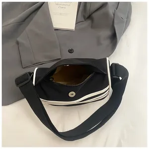 Black canvas crescent crossbody bag with white stitching and yellow inner lining