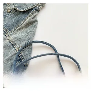 Detail aus blauem Denim-Stoff mit gewebten Rundschultergurten und Metallknopf-Hardware
