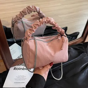 Sac oreiller rose froncé avec poignées et chaîne argentée sur une surface réfléchissante