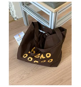 Close-up of brown canvas tote bag featuring metal zipper closure and high-quality seams