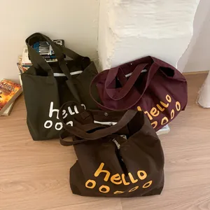 Three canvas tote bags in olive, wine, and brown with hello print and shoulder straps