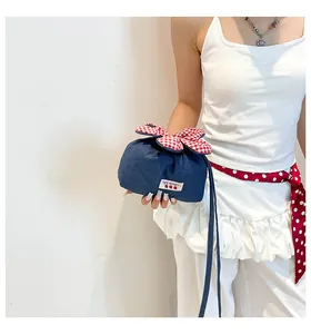 Detail der Kordelzugtasche aus dunkelblauem Denim mit rot-weißem Karomuster-Dekor