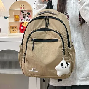 Detail van kakikleurige nylon rugzak met zwarte rits en witte panda ster pluche hanger