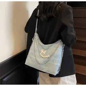Detail of light blue glitter tote bag with silver butterfly and pearl chain ornaments