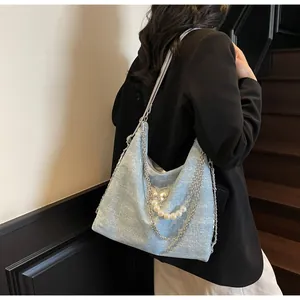 Detailed close-up of light blue glitter tote bag with butterfly charm and pearl chain