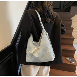 Detail of light blue tote with butterfly logo, silver chain and pearl strap decor