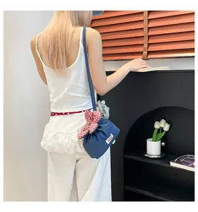Blaue Denim-Umhängetasche mit rot karierter Schleife getragen von einem Modell