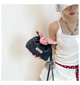 Detail der blauen Denim-Tasche mit rot-weißer Karoschleife und Erdbeer-Etikett