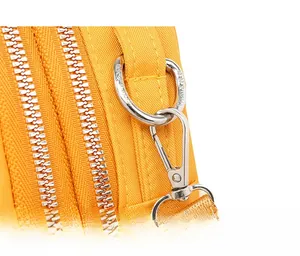 Detailed close-up of silver dual zippers and metallic hooks on yellow canvas bag