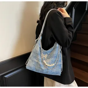 Detail of light blue hobo bag with silver chains, pearl charms and butterfly accent