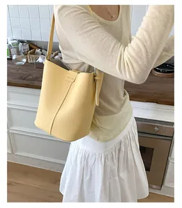 Gros plan d'un sac seau en cuir jaune à motif lychee avec texture souple et boucle en métal